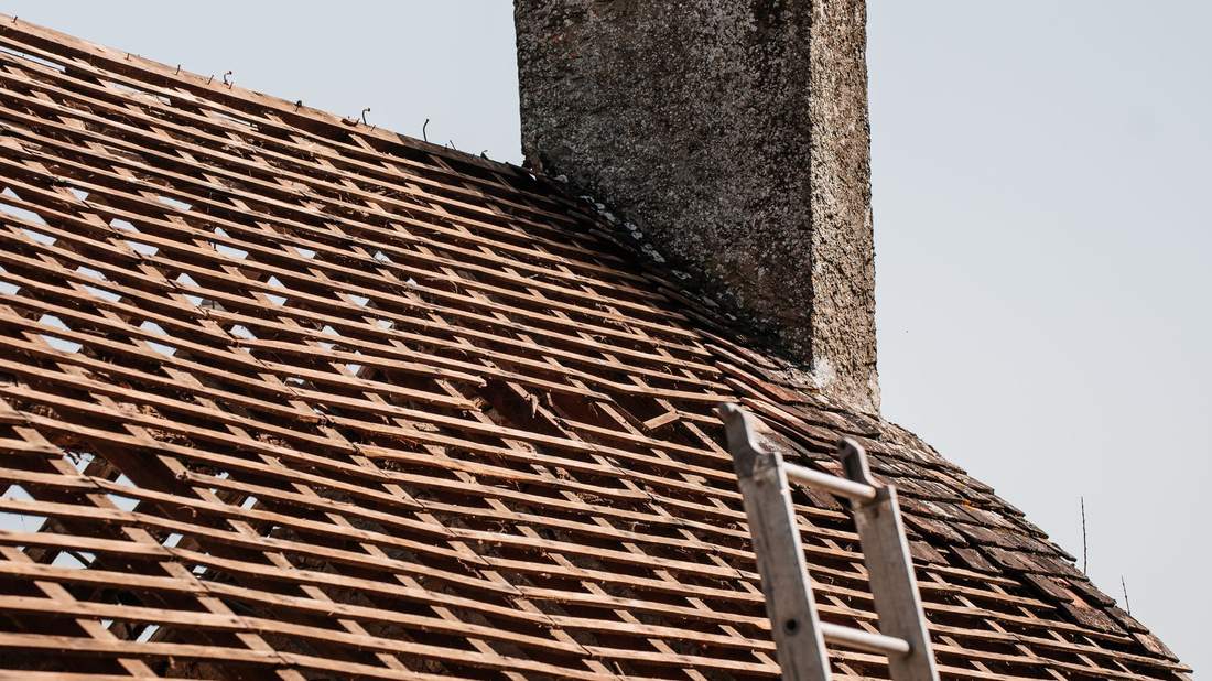 Intervention sur une toiture avec échelle appuyée près d'une cheminée